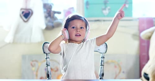 Child Listens to Music on Pink Headphones