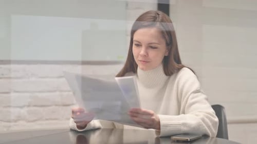 Happy Woman Laughing After Reading Documents in Office