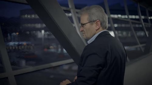 Man In Suit Looks Out At City At Night