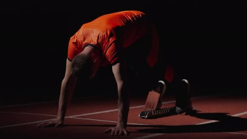 Male Athlete Preparing for a Sprint in the Dark