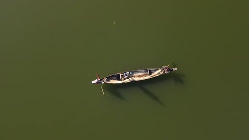 Luftaufnahme von oben nach unten eines kleinen Holzboots in einem See und Fischern, die traditionell Fische mit einem Netz fangen