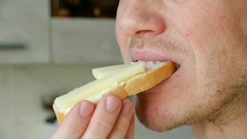 Young Man Eating a Butter and Cheese Sandwich for Breakfast