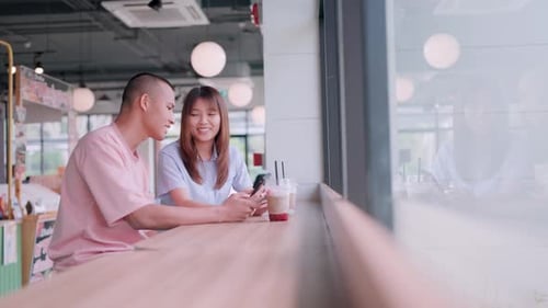 Couple looking at mobile phone while talking lovingly and expressing their love in a restaurant