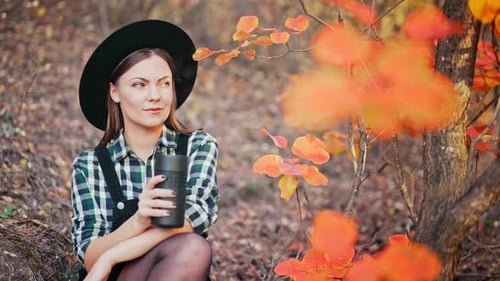 Hipster Woman Drinking Hot Coffee or Tea Thermos Golden Park Forest in Autumn