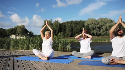 Adults Practice Yoga Poses on Wooden Dock by Lake