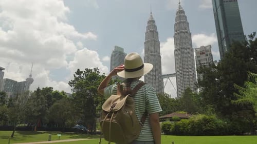Female tourist in hat with backpack is enjoying cityscape