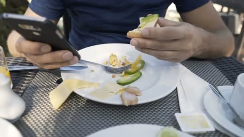 Man Eating Meal and Texting on Smartphone Sitting in Cafe 30s