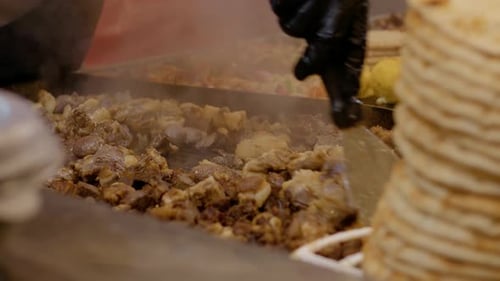 Street food vendor cooking meat on hot plate