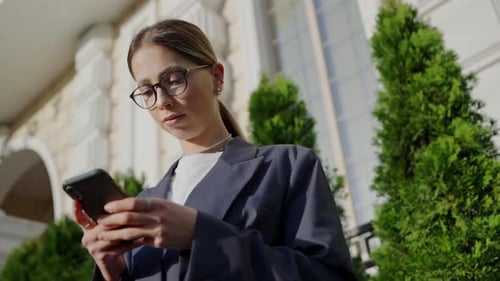 Professional Woman Using Smartphone Outside a Historic Building