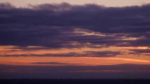 Evening clouds in the orange light of sunset rays, time lapse. Sunset sky with red light