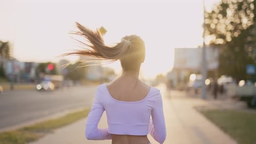 A Young Woman Runner is Training in the Summer Within a City