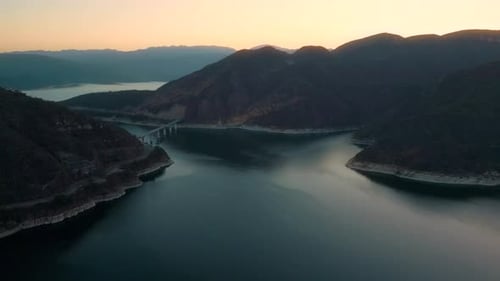 Aerial drone flying over a lake, water dam, with mountains at sunrise. Beautifull dreamy landscape