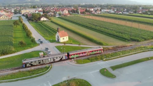 Train Passes Rural Railway Crossing, Farm Fields, Distant Town, AERIAL