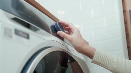 Close-up woman hand pushing washing machine buttons for setting program or start laundry