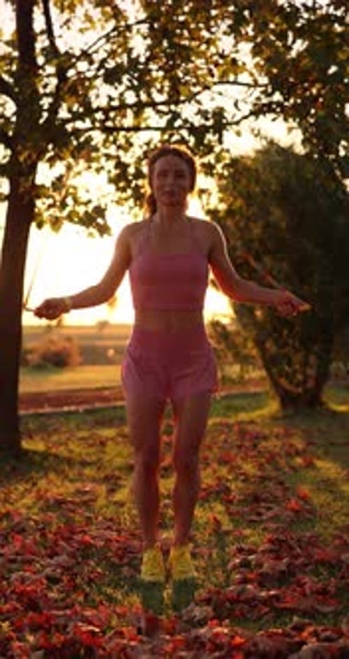 Happy woman jump rope outdoors in autumn park