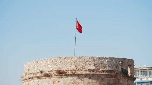 Stone Tower with Turkish Flag Against Blue Sky