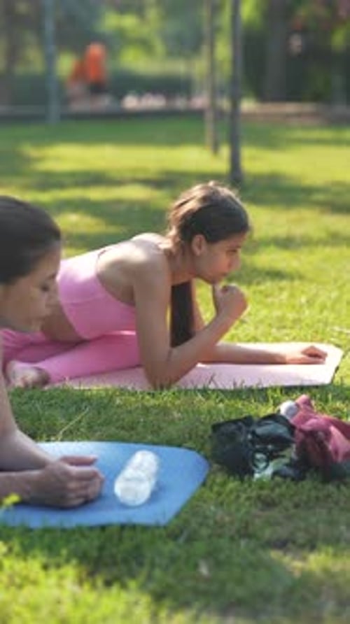 A Sporty and Beautiful Mother and Her Adult Daughter are Practicing Yoga in the Urban Park