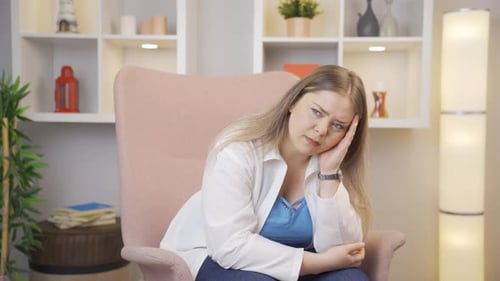Contemplative Woman Thinking in Armchair Inside Home