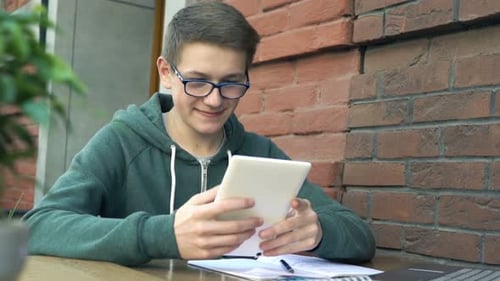 Young Teenager Working with Tablet While Studying in Cafe in City Alone