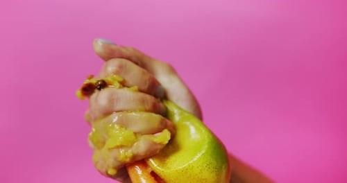 Hand Squeezing Ripe Mango Releasing Juice