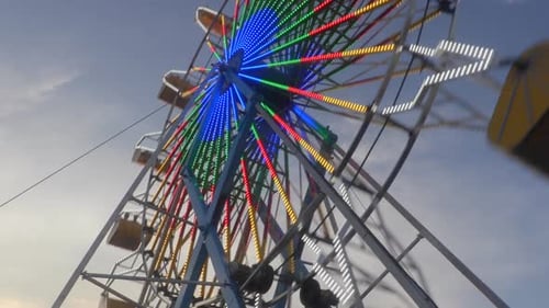 Ferris Wheel Rotating With Colorful Lights in Daytime