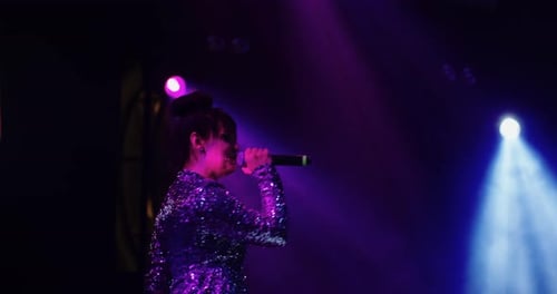 Woman Singing on Stage with Blue and Purple Lights