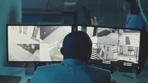 Man Monitors Security Cameras in Office at Night