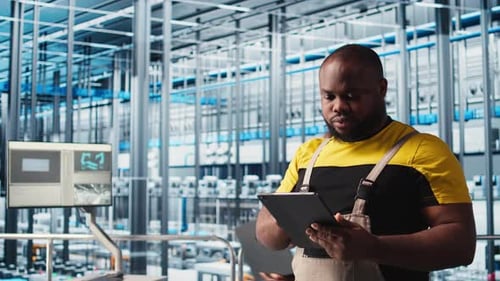 Un ingénieur d'usine intelligente supervise le fonctionnement des bras robotiques et des chaînes de montage
