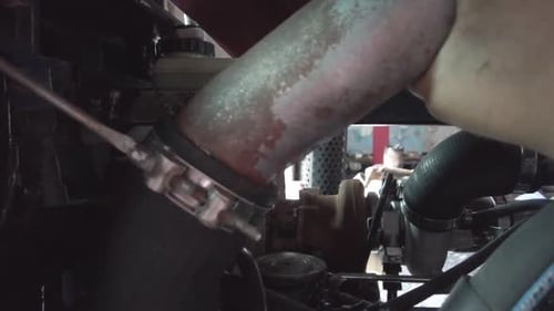 Mechanic Adjusting Clamp on Engine