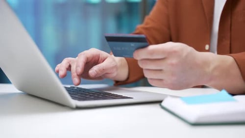 Close up of male hands typing on laptop to make online transaction with credit card at desk