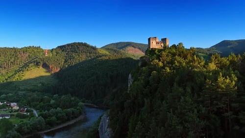 Approaching the walls of the castle on the high rock. Narrow river flows at the foot.