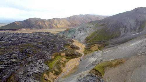 Mountain valley surrounded by lava fields in Landmannalaugar - Icelandic Highlands Aerial drone shot