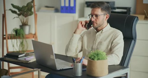 Geschäftsmann spricht auf Smartphone und benutzt Laptop