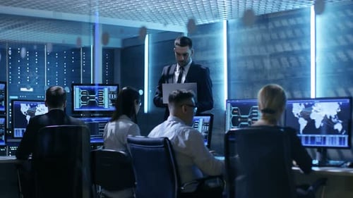 Professional IT Engineers Working in System Control Center Full of Monitors and Servers. Possibly