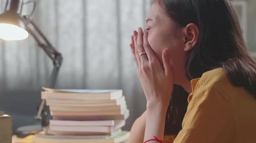 Close Up Of Young Asian Female Studying At Home Yawning And Sleeping While Reading Books
