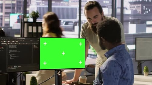 Der Systemadministrator führt mit einem Kollegen Software-Debugging auf einem Greenscreen-PC durch
