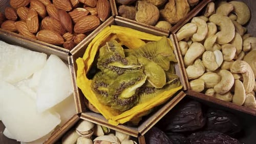 A set of dried fruits and nuts in a wooden box. Rotate close-up.