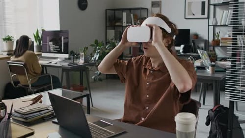 Web Developer Using VR Headset and Typing on Laptop in Office