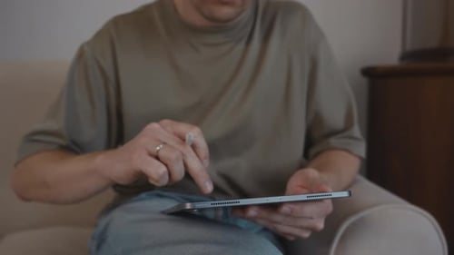 Man Using Tablet with Stylus Pen on Couch