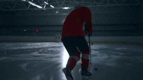 Exciting Video Footage of a Hockey Player in a Red Jersey Training on a Dark Ice Arena Showcasing