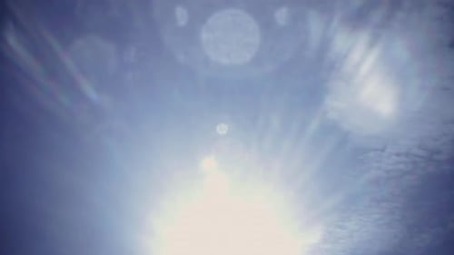 Lomography holga lens flare overlay with summer sun and blue sky with fluffy clouds background.