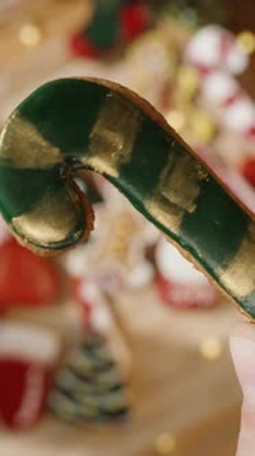 Vertical video. Hand Displaying Green and Gold Candy Cane Cookie, Sunny Christmas Morning.