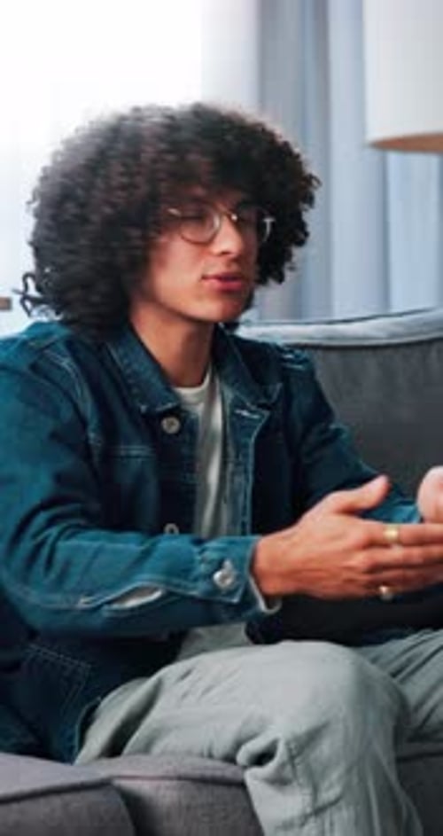 Young Adult Man Sitting and Gesturing Indoors