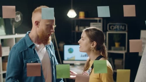 Young business partners brainstorming ideas on sticker board in modern hipster office