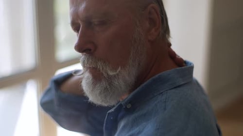 Senior Man Massaging His Neck Close Up Indoors