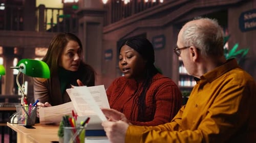 Une équipe mature d'interprètes répétant le dialogue du script ensemble dans une bibliothèque