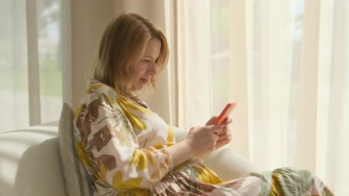 Woman Using Smart Phone Relaxing Indoors During Daytime