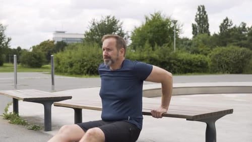 A Handsome Middleaged Caucasian Man Does Bench Dips in a Park