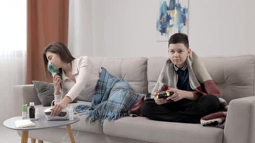 Woman Using Nebulizer, Teen Playing Video Game