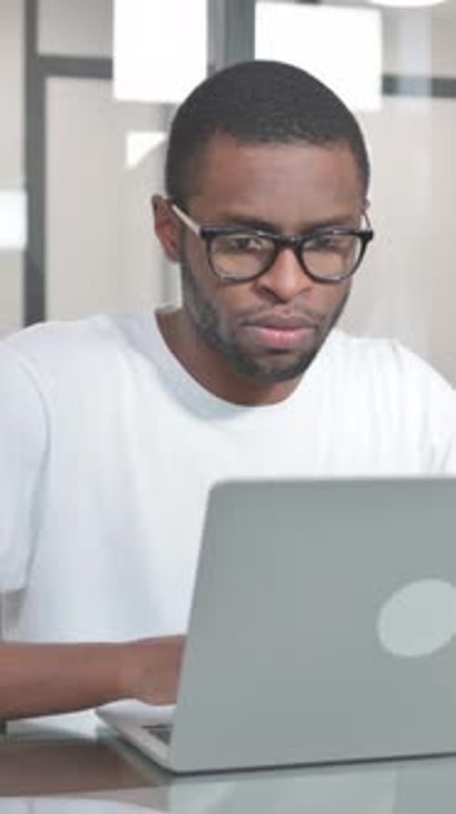 Young Man Works on Laptop in Modern Workplace